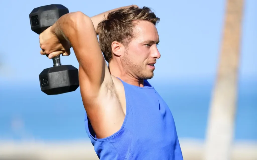 Overhead dumbbell tricep extension performed by an athlete