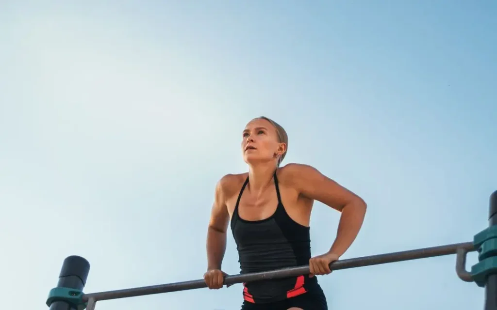 a woman doing pull-ups outdoors