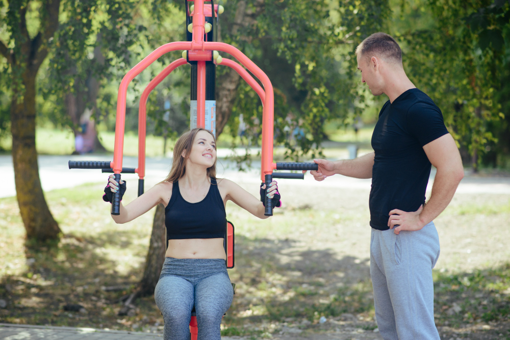 Femme utilisant une machine de musculation extérieure avec un partenaire dans un parc