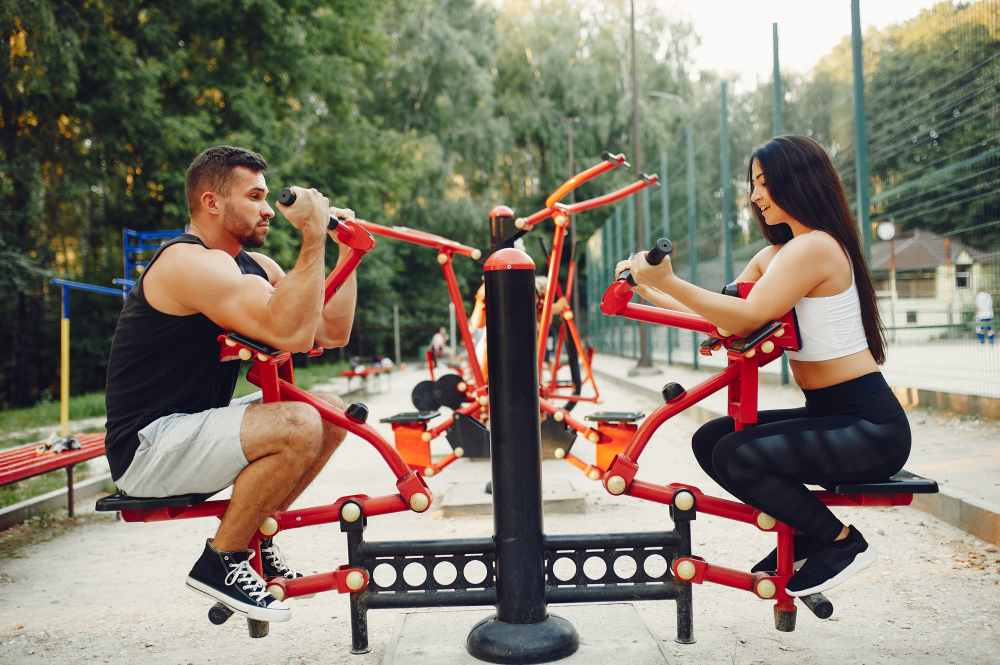 Couple s'entraînant sur des machines de musculation extérieure dans un parc
